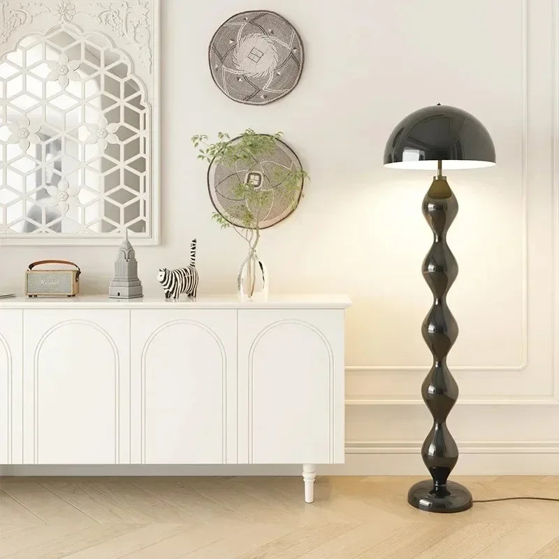 Black floor lamp in a room with white walls, decorative mirrors, and a white cabinet.