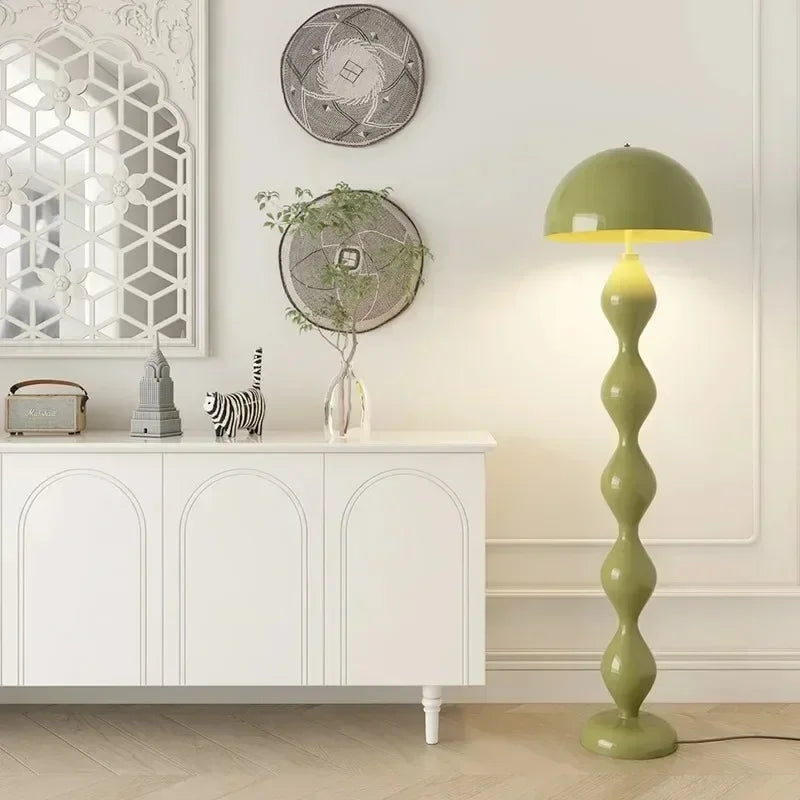 Green floor lamp in a room with decorative elements and a white cabinet.