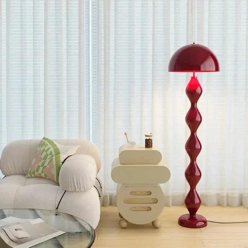 Red floor lamp in a living room setting with a beige armchair and small table.