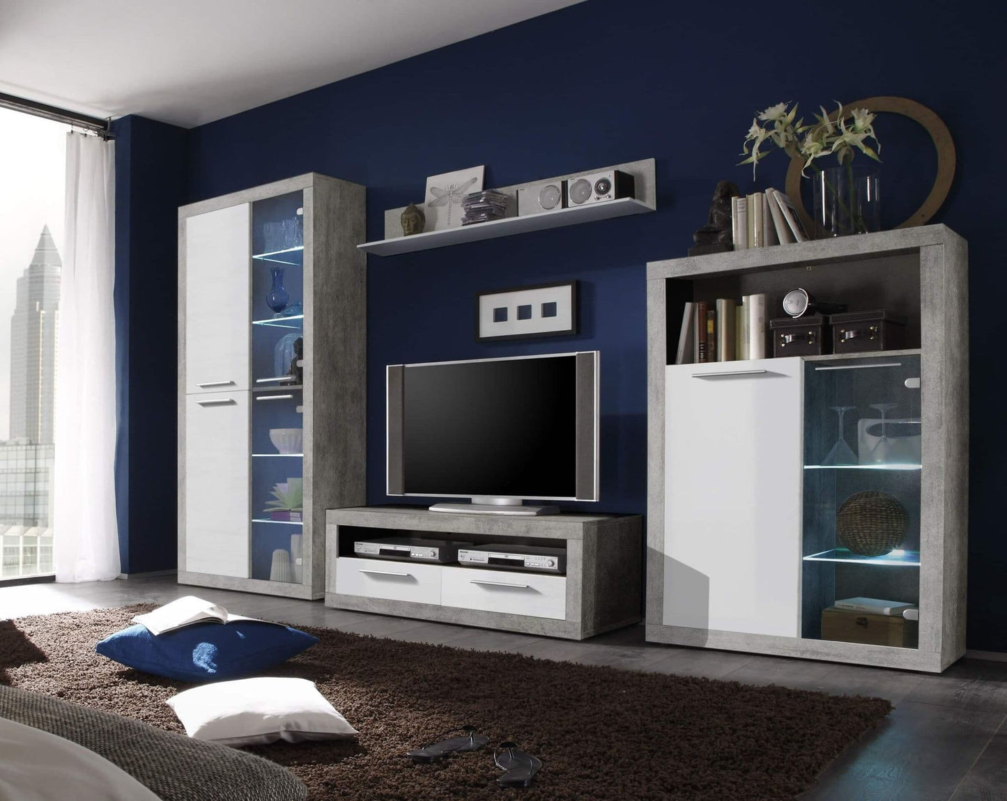 Modern living room display cabinet in white and grey high gloss finishing, with a television and entertainment unit against a blue wall.