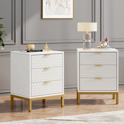 Two white nightstands with gold accents in a room with gray walls and a lamp.