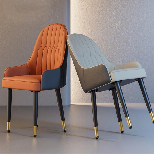 Two modern chairs, one orange and one gray, with gold accents on black legs, against a neutral background.