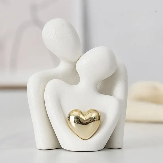 Ceramic figurine of two people embracing with a gold heart in the center on a light background