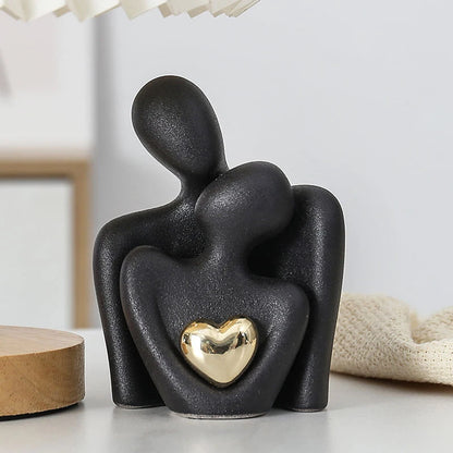 Black abstract sculpture with a gold heart on a white surface