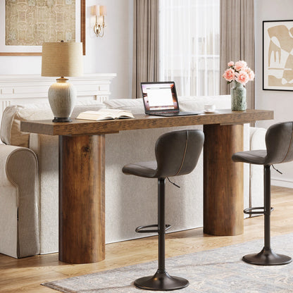 Wooden dining table with a laptop, lamp, and flowers in a room with a couch and chairs.