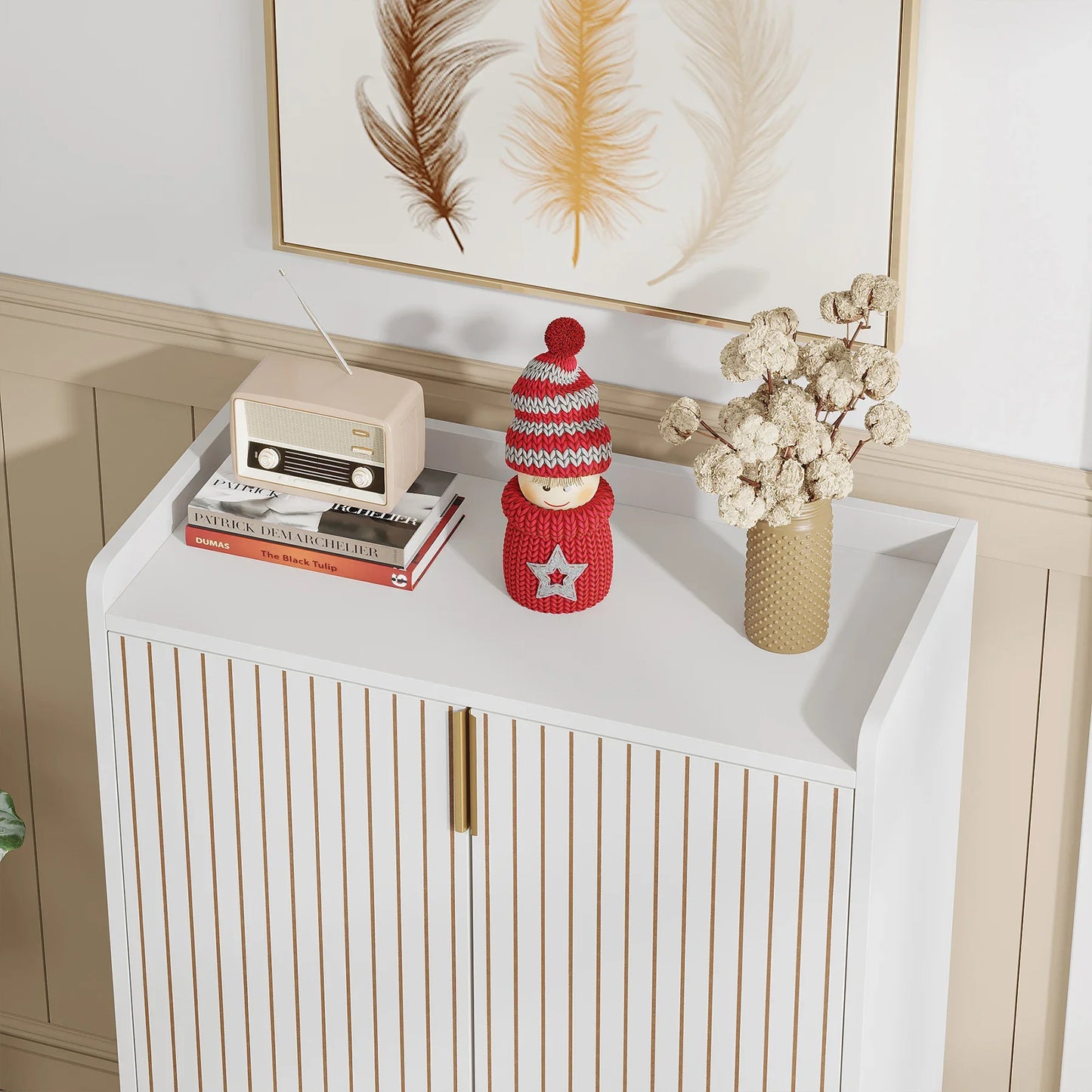 White cabinet with decorative items including a knitted doll, books, and a vase with dried flowers.