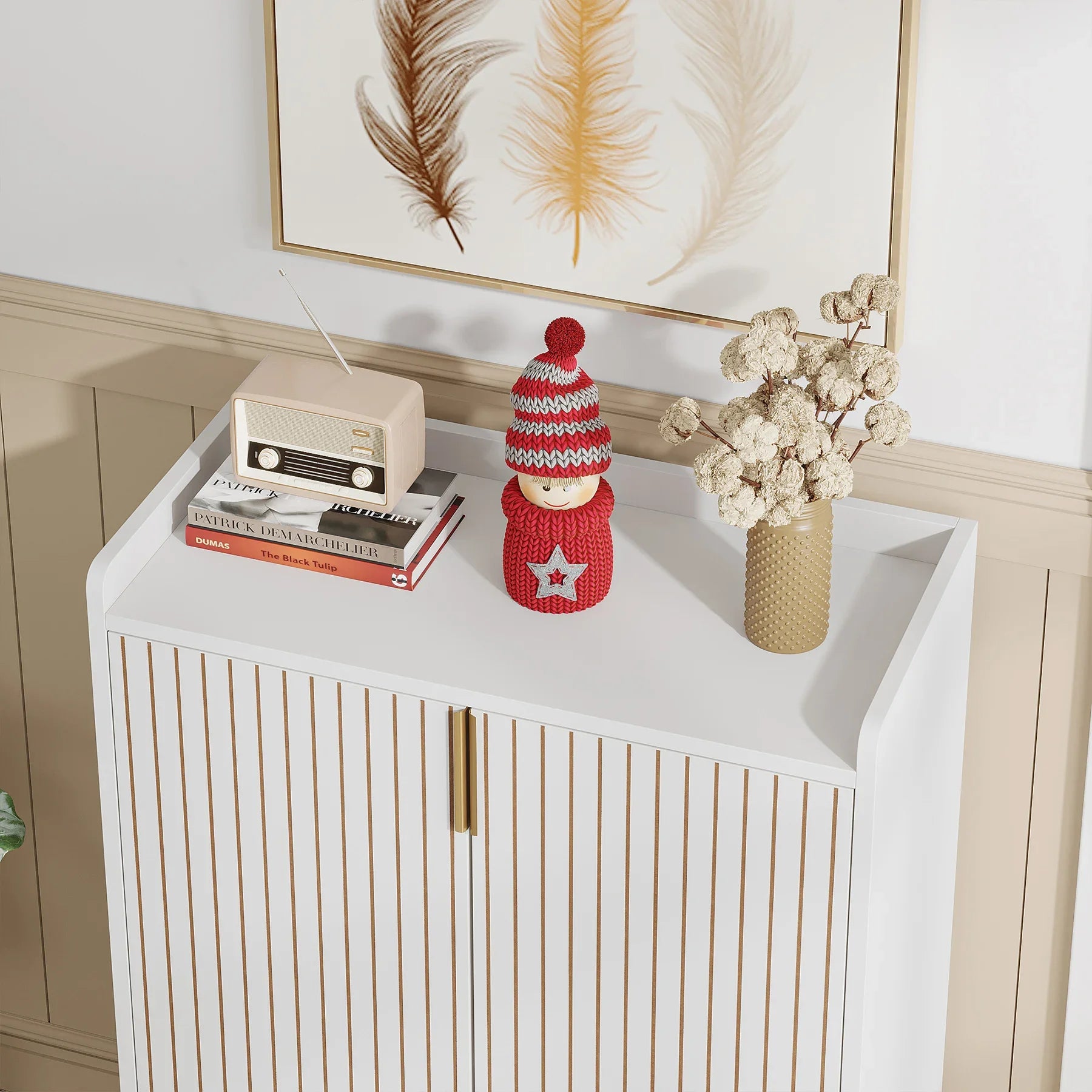 White cabinet with decorative items including a knitted doll, books, and a vase with dried flowers.
