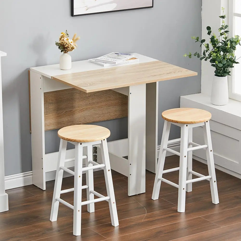 Wooden dining table with a white base and two stools in a room with gray walls and a window.