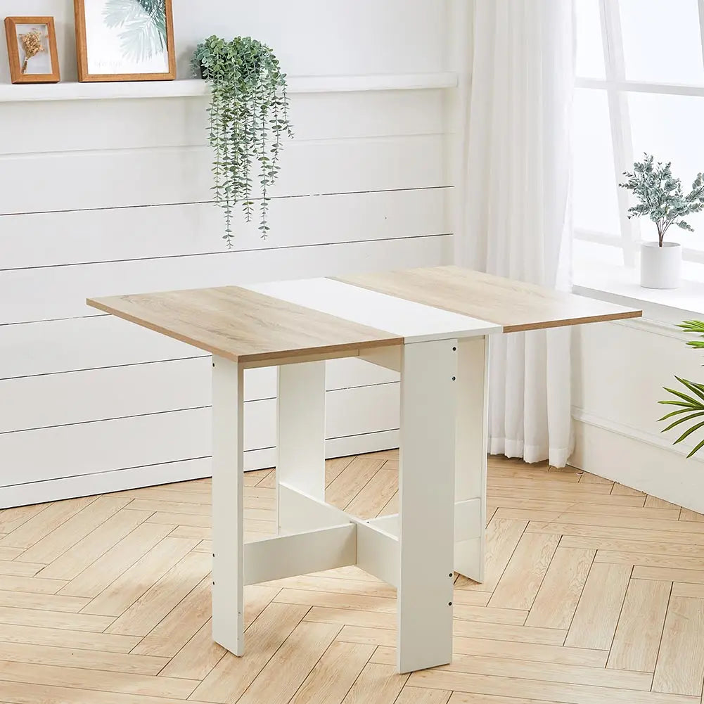 Wooden extending table with white base in a room with plants and a window.
