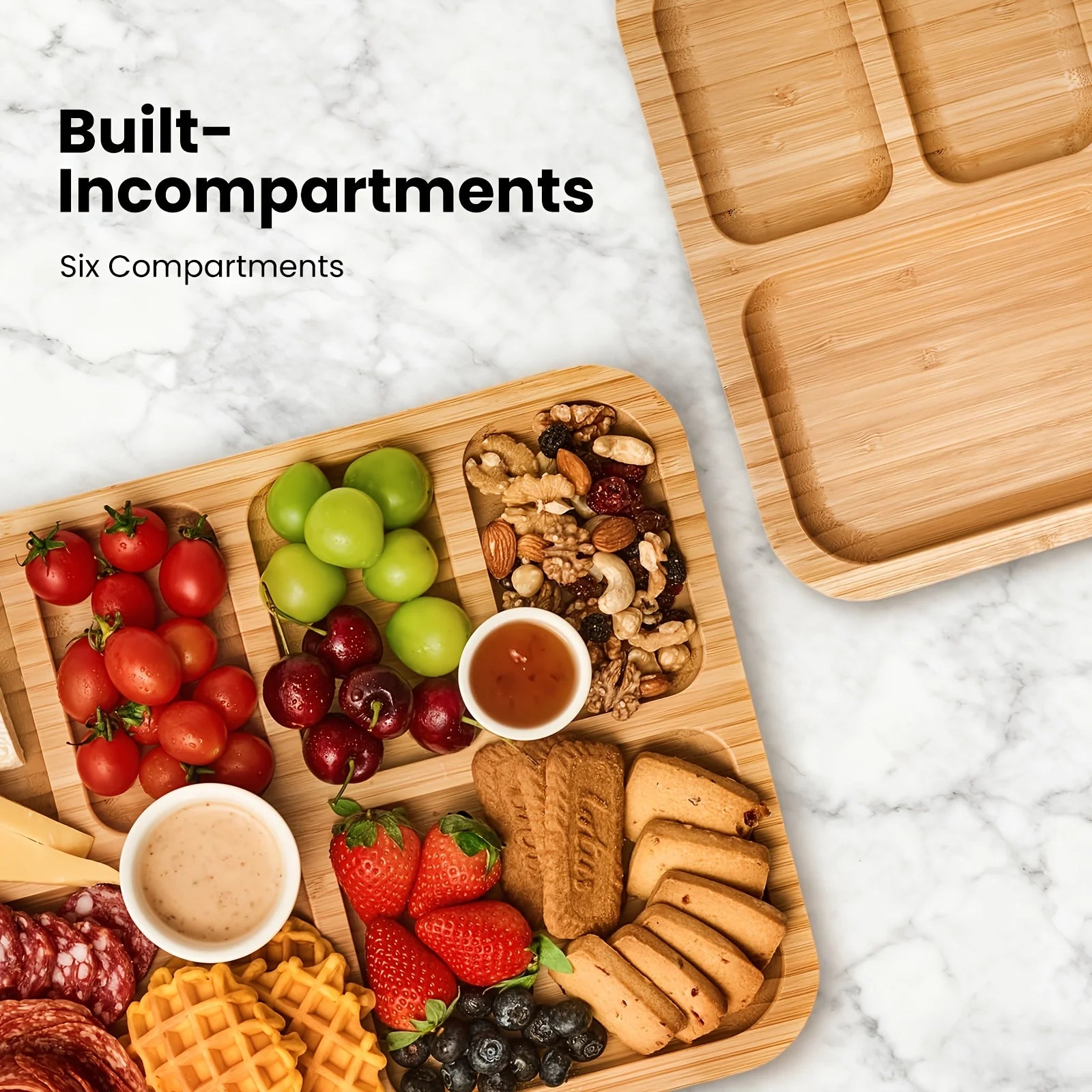 Wooden tray with compartments filled with fruits, nuts, and cookies on a marble surface.