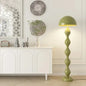 Green floor lamp in a room with decorative elements and a white cabinet.