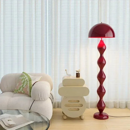 Red floor lamp in a living room setting with a beige armchair and small table.