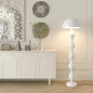 White floor lamp next to a white cabinet with decorative items in a room.